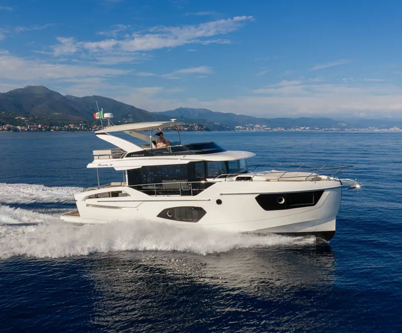 The Image of The 2028 Absolute Navetta 50 cruises on calm waters with a scenic coastline in the background. - 0