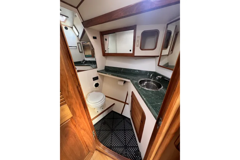 Slide: The Image of Compact bathroom in 1991 Perry 51 yacht with green marble countertop and wooden accents. - 89