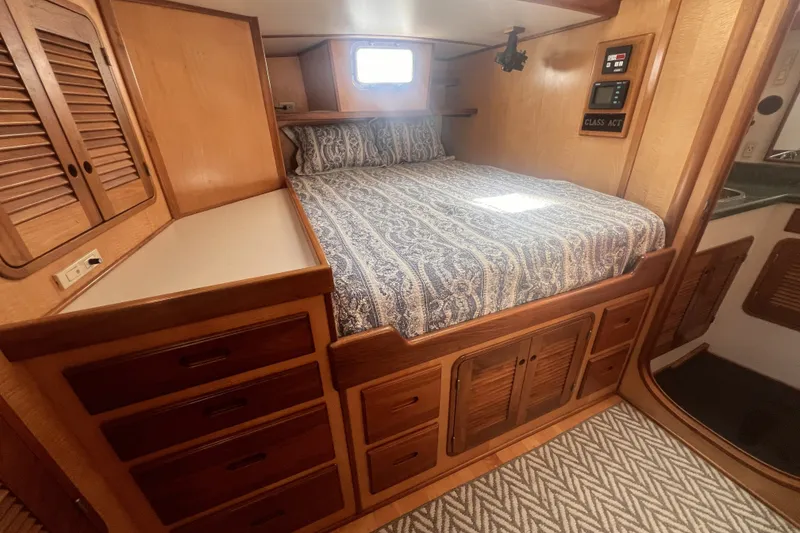 Slide: The Image of Cozy cabin interior of 1991 Perry 51 yacht with wooden storage and patterned bedding. - 77
