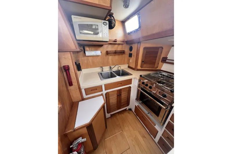 Slide: The Image of Compact kitchen in a 1991 Perry 51 yacht with stove, microwave, and dual sink. - 55