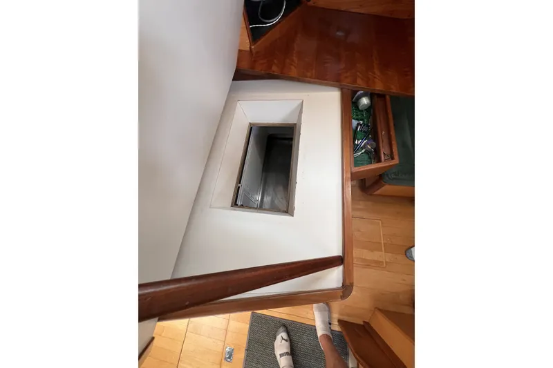 Slide: The Image of Interior view of a 1991 Perry 51 yacht, featuring a wooden staircase and storage compartment. - 64