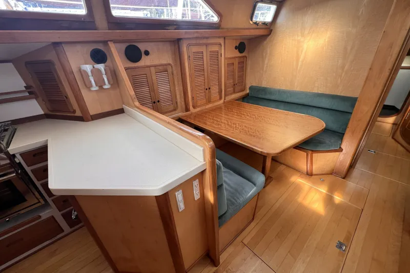 Slide: The Image of Cozy 1991 Perry 51 yacht interior with wooden dining area and cushioned seating. - 62