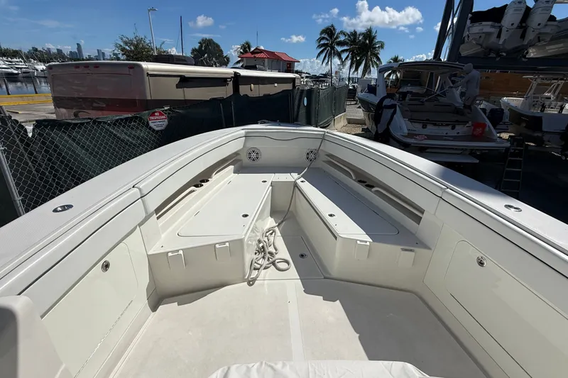 Slide: The Image of 2015 Jupiter 34 FS boat interior with seating and storage, docked near palm trees. - 21
