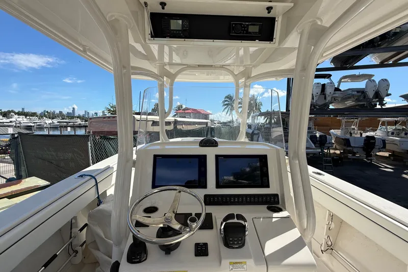 Slide: The Image of 2015 Jupiter 34 FS boat cockpit with dual screens and steering wheel, docked at marina. - 15