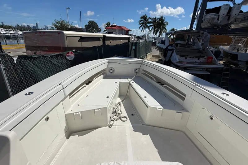 Slide: The Image of 2015 Jupiter 34 FS boat interior with seating and storage, docked near palm trees and marina. - 22