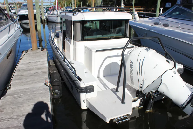 Slide: The Image of 2019 Axopar Brabus 28 Cabin boat docked with Mercury engine visible. - 4