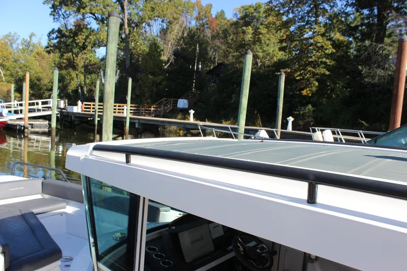 Slide: The Image of 2019 Axopar Brabus 28 Cabin boat docked near a wooden pier, surrounded by trees. - 11