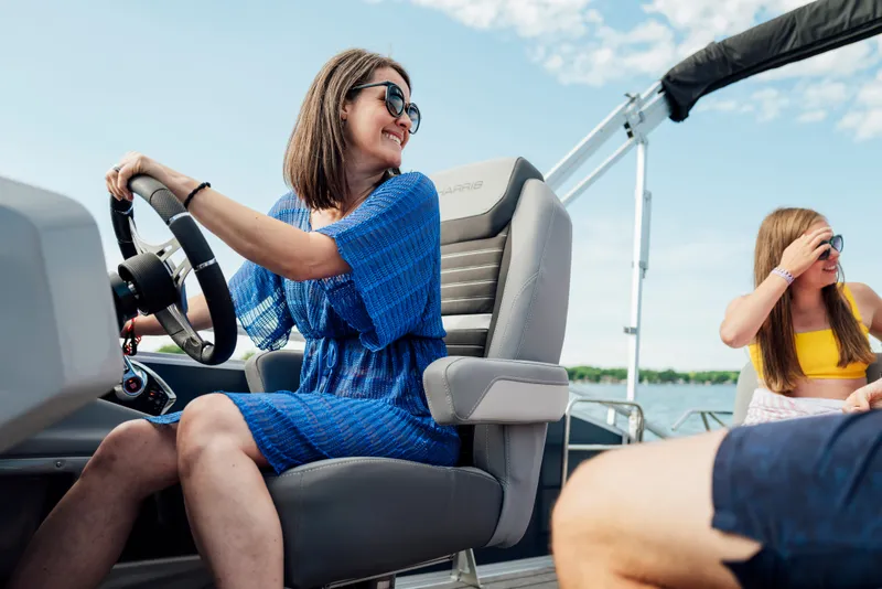 Slide: The Image of A woman steers a Harris Solstice 230 boat while another person enjoys the view. - 30