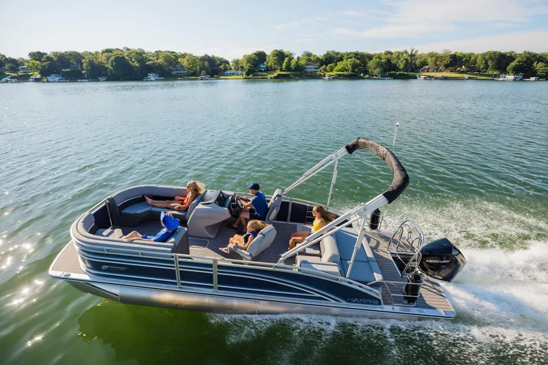 Slide: The Image of A Harris Solstice 230 pontoon boat cruising on a lake with several people on board. - 24