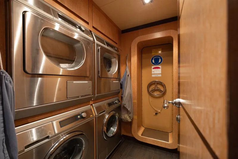 Slide: The Image of Laundry room with stacked stainless steel washers and dryers on a 2009 Mangusta 165 yacht. - 63