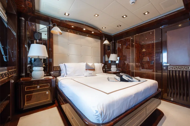 Slide: The Image of Luxurious bedroom interior on 2009 Mangusta 165 yacht, featuring elegant wood finishes and plush bedding. - 38