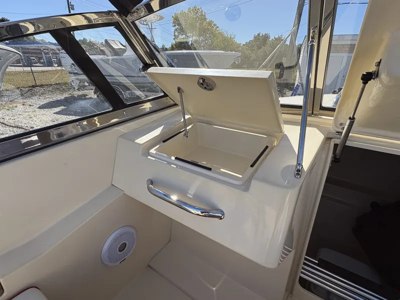 Slide: The Image of The image shows the cockpit of a 2020 Rossiter 20 boat with an open storage compartment. - 24
