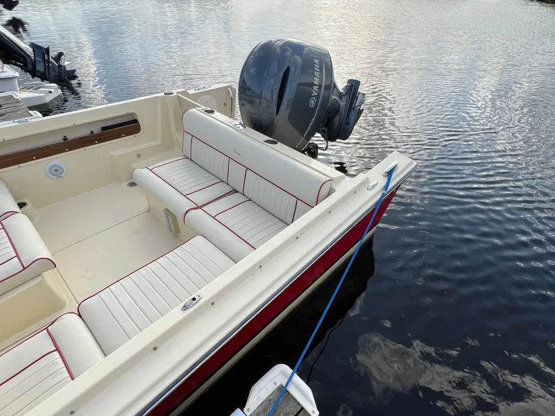 Slide: The Image of A 2020 Rossiter 20 boat with cream seats and red accents, docked by the water. - 15