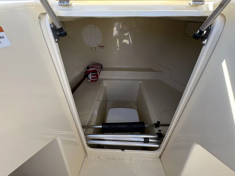 Slide: The Image of The image shows the storage area of a 2020 Rossiter 20 boat with rods and a cushion. - 30