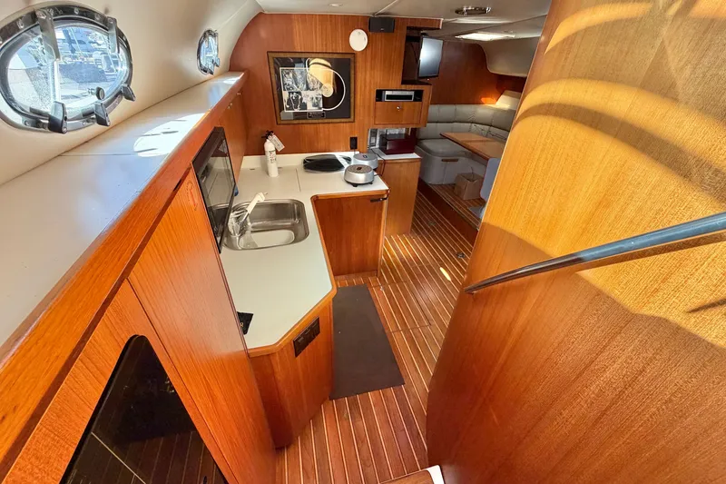 Slide: The Image of Interior of 1998 Tiara Yachts 4000 Express, featuring wood finishes and compact kitchen area. - 13