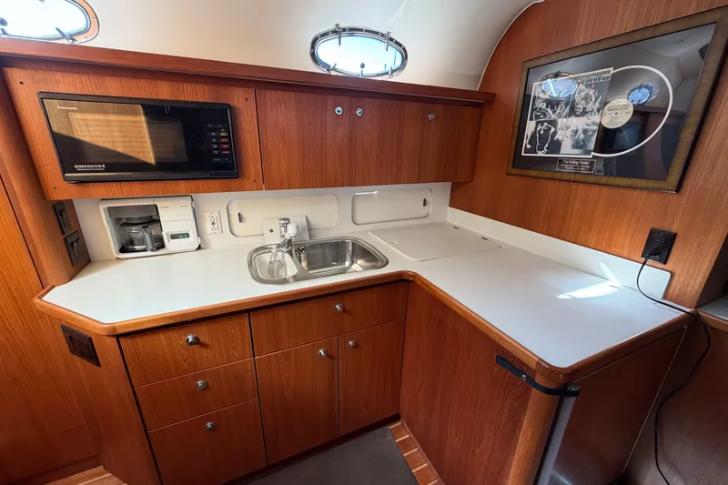 Slide: The Image of 1998 Tiara Yachts 4000 Express galley with wood cabinetry, sink, microwave, and framed artwork. - 15
