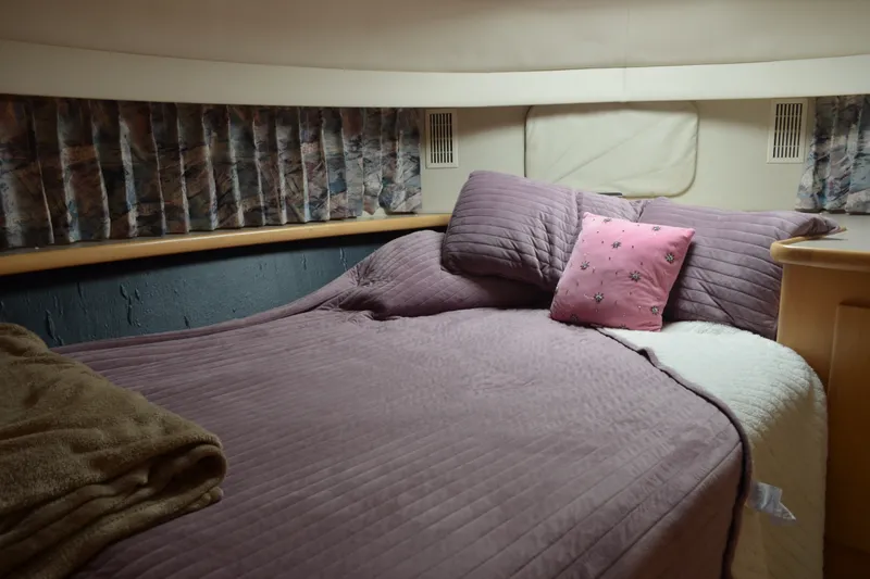 Slide: The Image of Cozy bedroom in 1996 Carver 440 Aft Cabin Motor Yacht with purple bedding and floral pillow. - 49