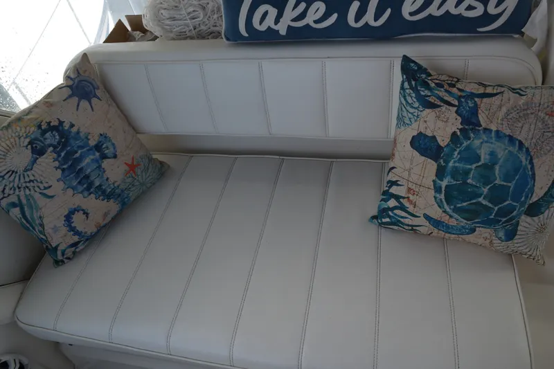 Slide: The Image of White leather seating with nautical-themed pillows on a 1996 Carver 440 Aft Cabin Motor Yacht. - 20