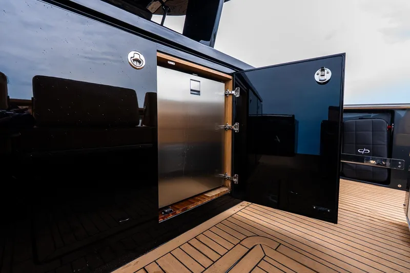 Slide: The Image of Open storage compartment on 2025 Pardo Yachts 43, featuring sleek black finish and wooden flooring. - 19