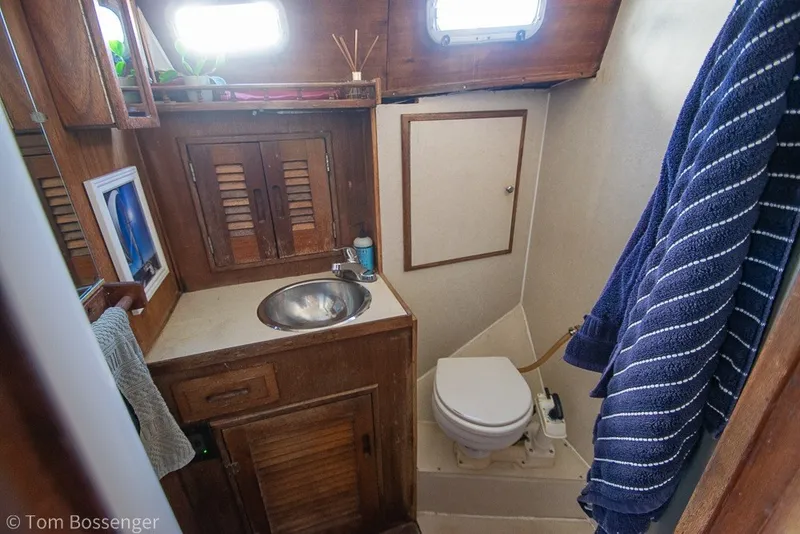 Slide: The Image of 1973 Challenger 32 boat bathroom with wooden cabinets, sink, and toilet. - 19
