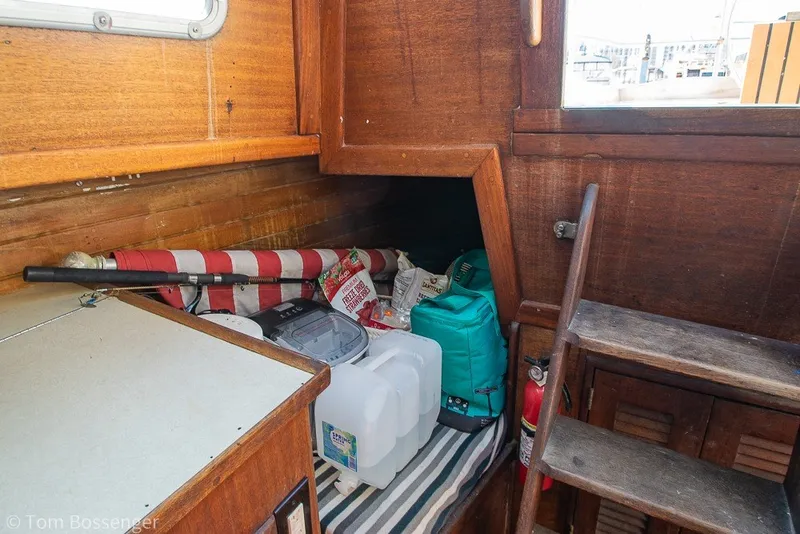Slide: The Image of Interior of a 1973 Challenger 32 sailboat with storage items and wooden cabinetry. - 21