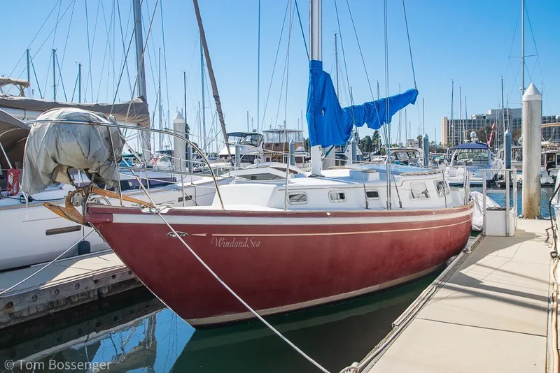 The Image of 1973 Challenger 32 sailboat docked in marina, featuring red hull and blue sail cover. - 1