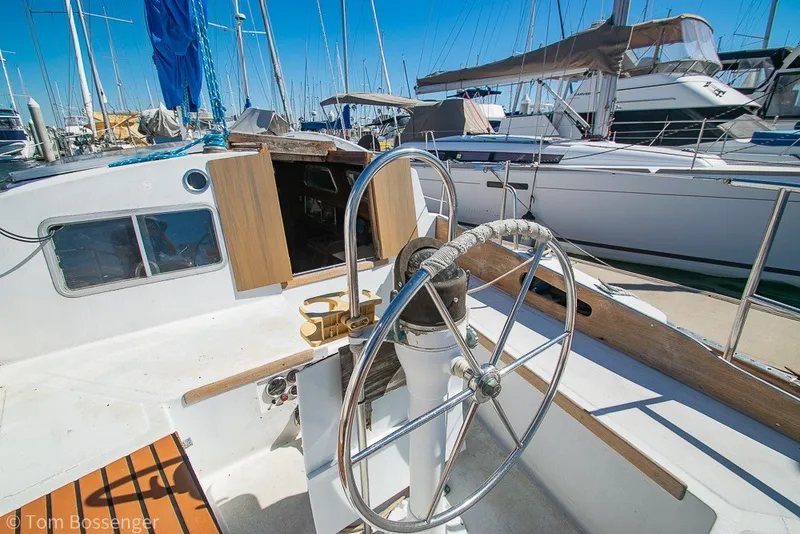 Slide: The Image of 1973 Challenger 32 sailboat cockpit with steering wheel, docked in a marina. - 27