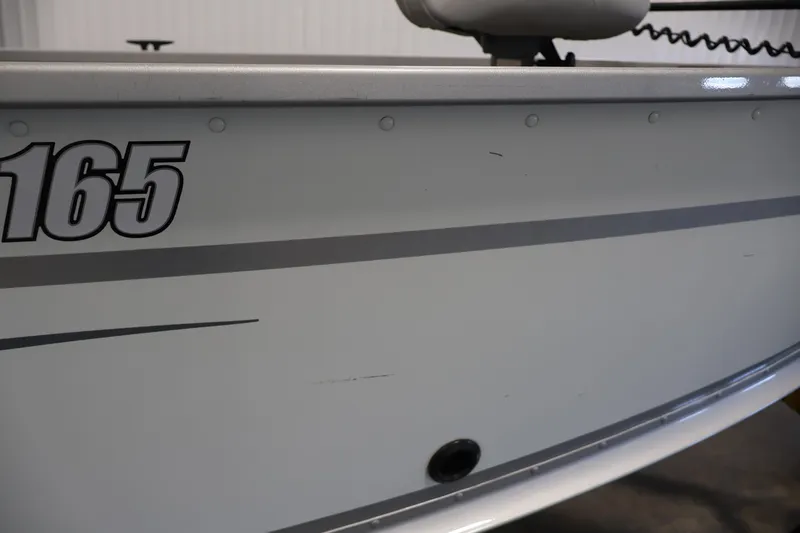Slide: The Image of 2015 Alumacraft Classic 165 Tiller boat side view with model number visible. - 35