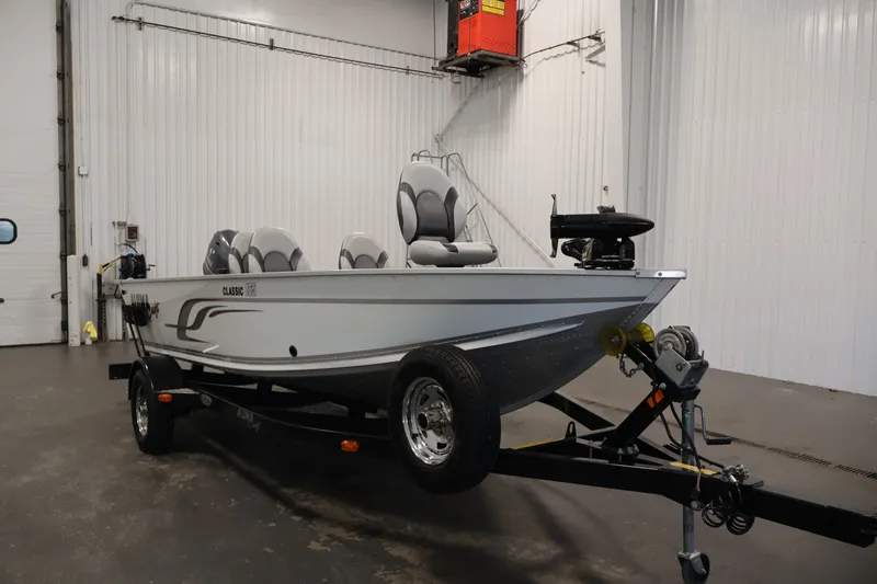 The Image of 2015 Alumacraft Classic 165 Tiller boat on trailer in indoor storage. - 0