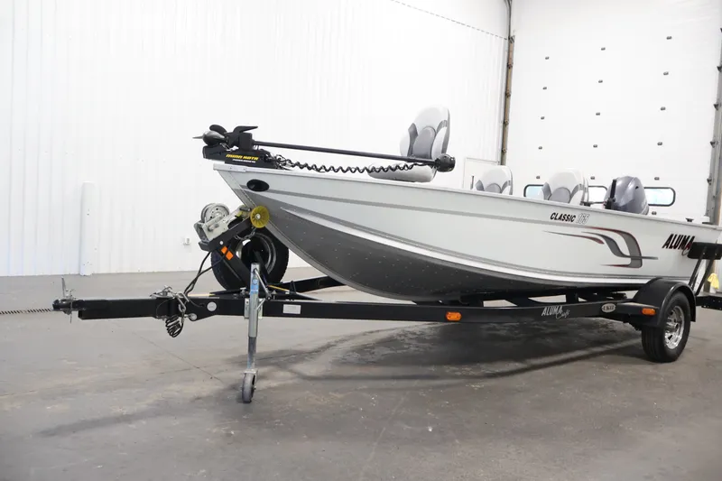 Slide: The Image of 2015 Alumacraft Classic 165 Tiller boat on trailer in indoor setting. - 33