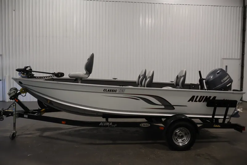 Slide: The Image of 2015 Alumacraft Classic 165 Tiller boat on trailer in indoor setting. - 8