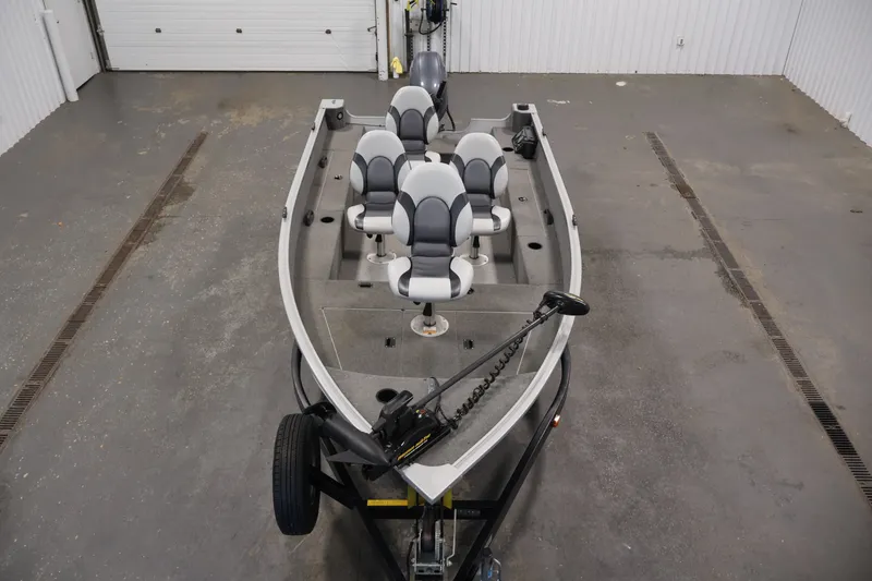 Slide: The Image of 2015 Alumacraft Classic 165 Tiller boat in a garage, featuring multiple seats and a trolling motor. - 9