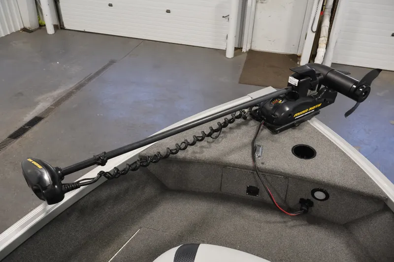 Slide: The Image of 2015 Alumacraft Classic 165 Tiller with Minn Kota trolling motor in a garage setting. - 15
