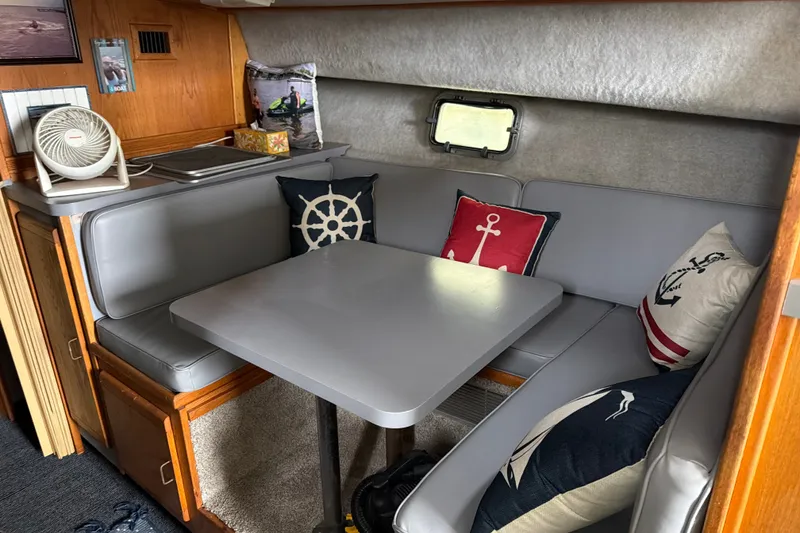Slide: The Image of 1988 Silverton 37 Convertible interior with nautical-themed cushions and compact dining area. - 10