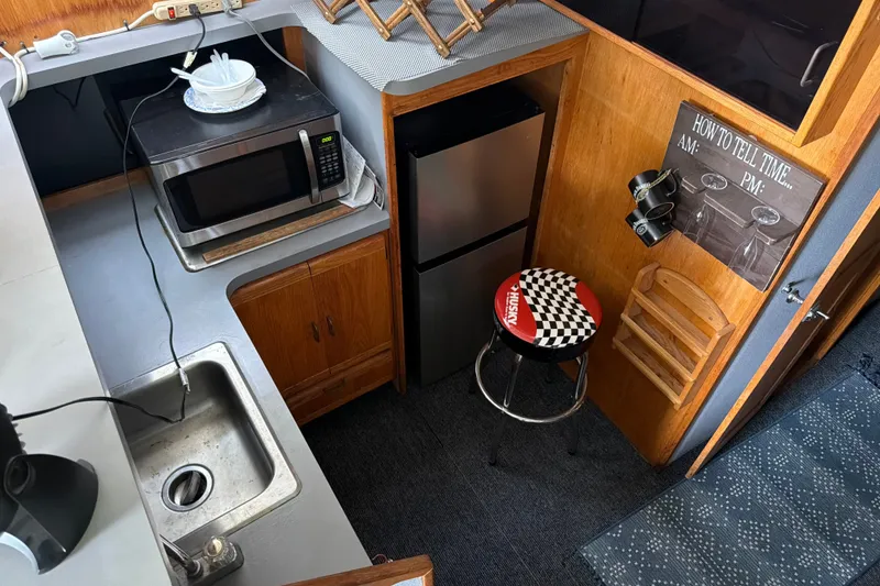 Slide: The Image of 1988 Silverton 37 Convertible kitchen with microwave, fridge, sink, and decorative stool. - 11