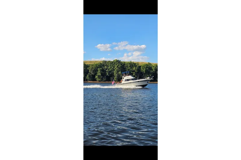 Slide: The Image of 1988 Silverton 37 Convertible cruising on a sunny day with scenic background. - 6
