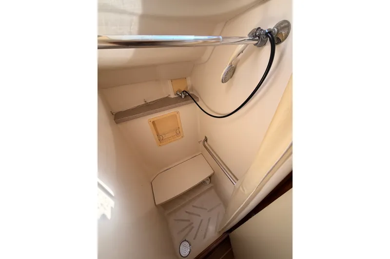 Slide: The Image of Compact shower area in a 2002 Hunter 460 boat, featuring a handheld showerhead and seating. - 71