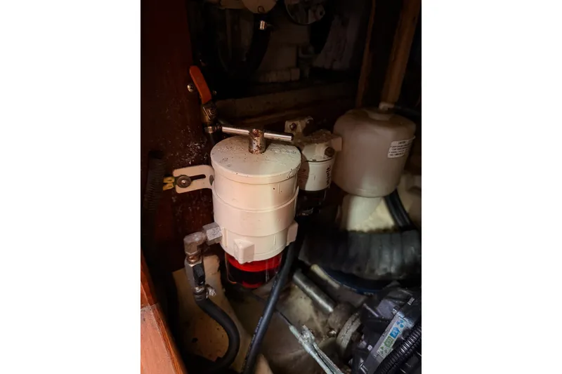 Slide: The Image of Engine compartment of a 2002 Hunter 460 sailboat, featuring fuel filter and hoses. - 79