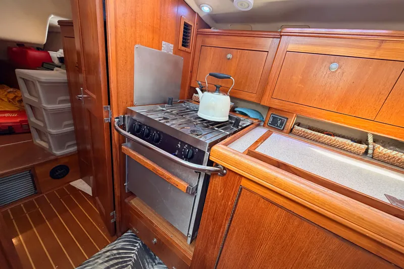Slide: The Image of Cozy 2002 Hunter 460 yacht kitchen with stove, kettle, and wooden cabinetry. - 43