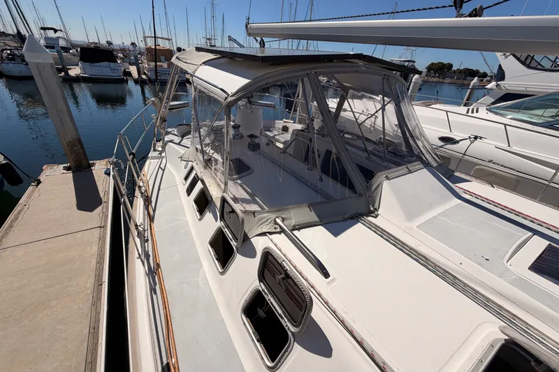 Slide: The Image of 2002 Hunter 460 sailboat docked at marina, featuring spacious deck and clear canopy. - 19