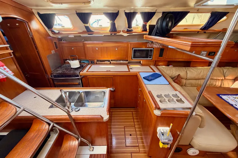 Slide: The Image of Interior of a 2002 Hunter 460 sailboat featuring a well-equipped kitchen and cozy seating area. - 38