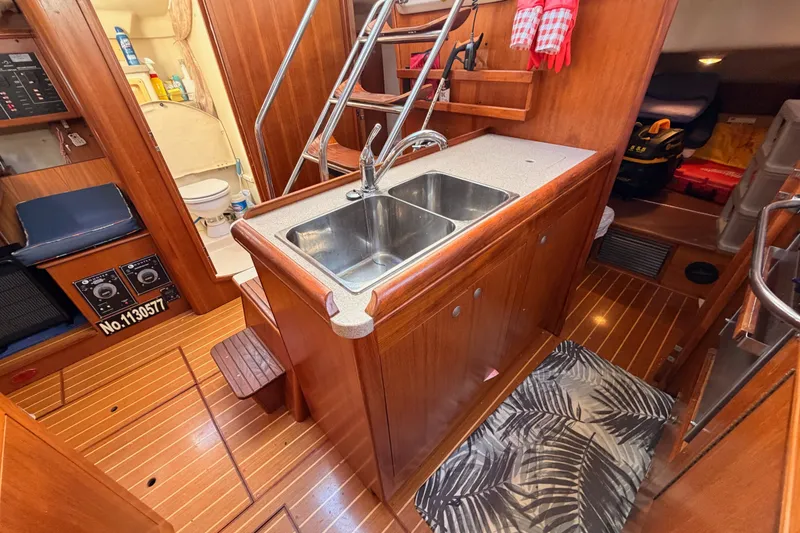Slide: The Image of Interior of a 2002 Hunter 460 yacht featuring a compact kitchen with wooden cabinetry. - 42