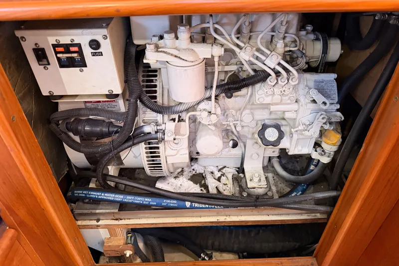Slide: The Image of Engine compartment of a 2002 Hunter 460 sailboat, featuring mechanical components and wiring. - 80
