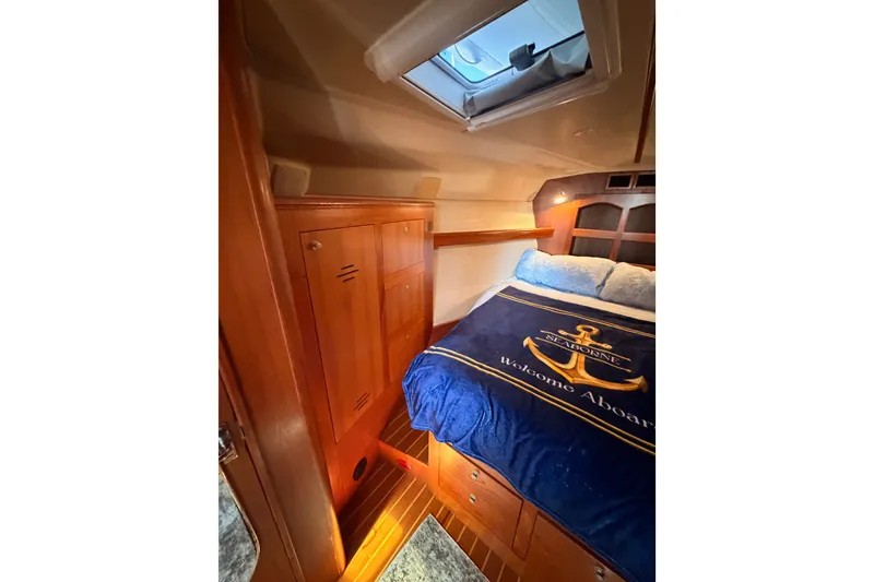 Slide: The Image of Cozy cabin interior of 2002 Hunter 460 sailboat with wooden finishes and nautical bedding. - 68
