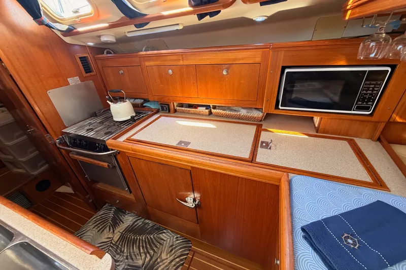 Slide: The Image of 2002 Hunter 460 yacht kitchen with stove, microwave, and wooden cabinetry. - 40