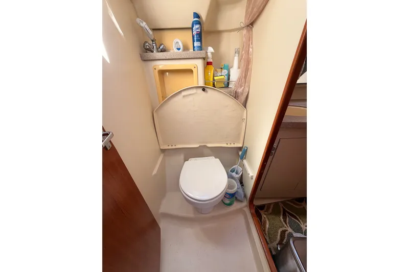 Slide: The Image of Compact bathroom in a 2002 Hunter 460 yacht, featuring a toilet and storage shelves. - 52