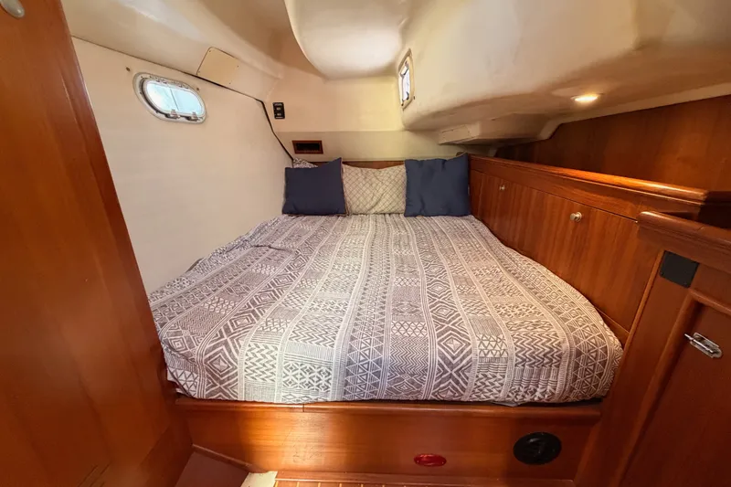 Slide: The Image of Cozy cabin interior of 2002 Hunter 460 sailboat with patterned bedding and wooden cabinetry. - 56
