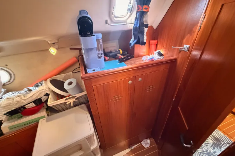 Slide: The Image of Interior of a 2002 Hunter 460 sailboat with wooden cabinetry and storage items. - 47