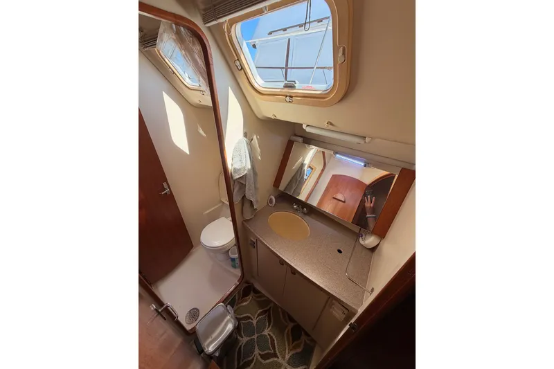 Slide: The Image of Bathroom interior of a 2002 Hunter 460 yacht with sink, mirror, and porthole window. - 53