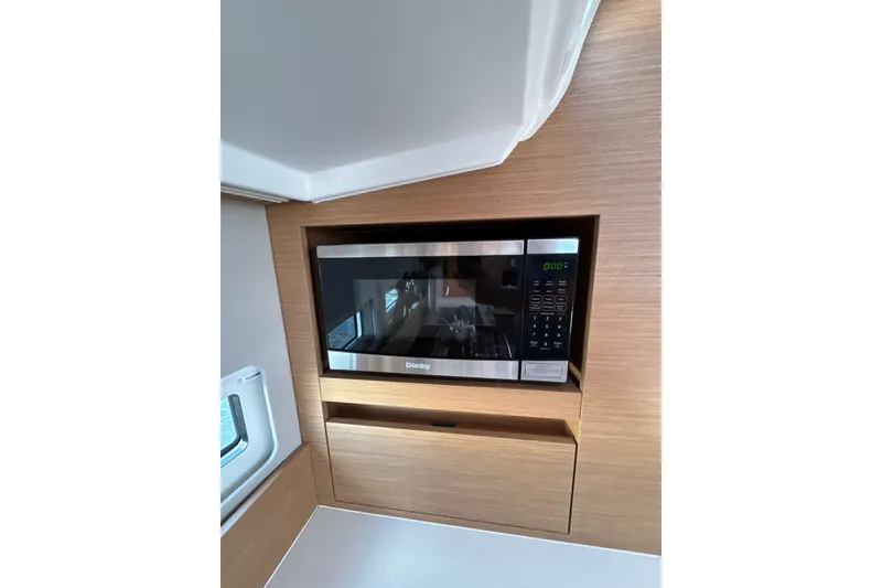 Slide: The Image of Microwave in Jeanneau Sun Odyssey 410 yacht interior, 2022 model, with sleek wood paneling. - 15
